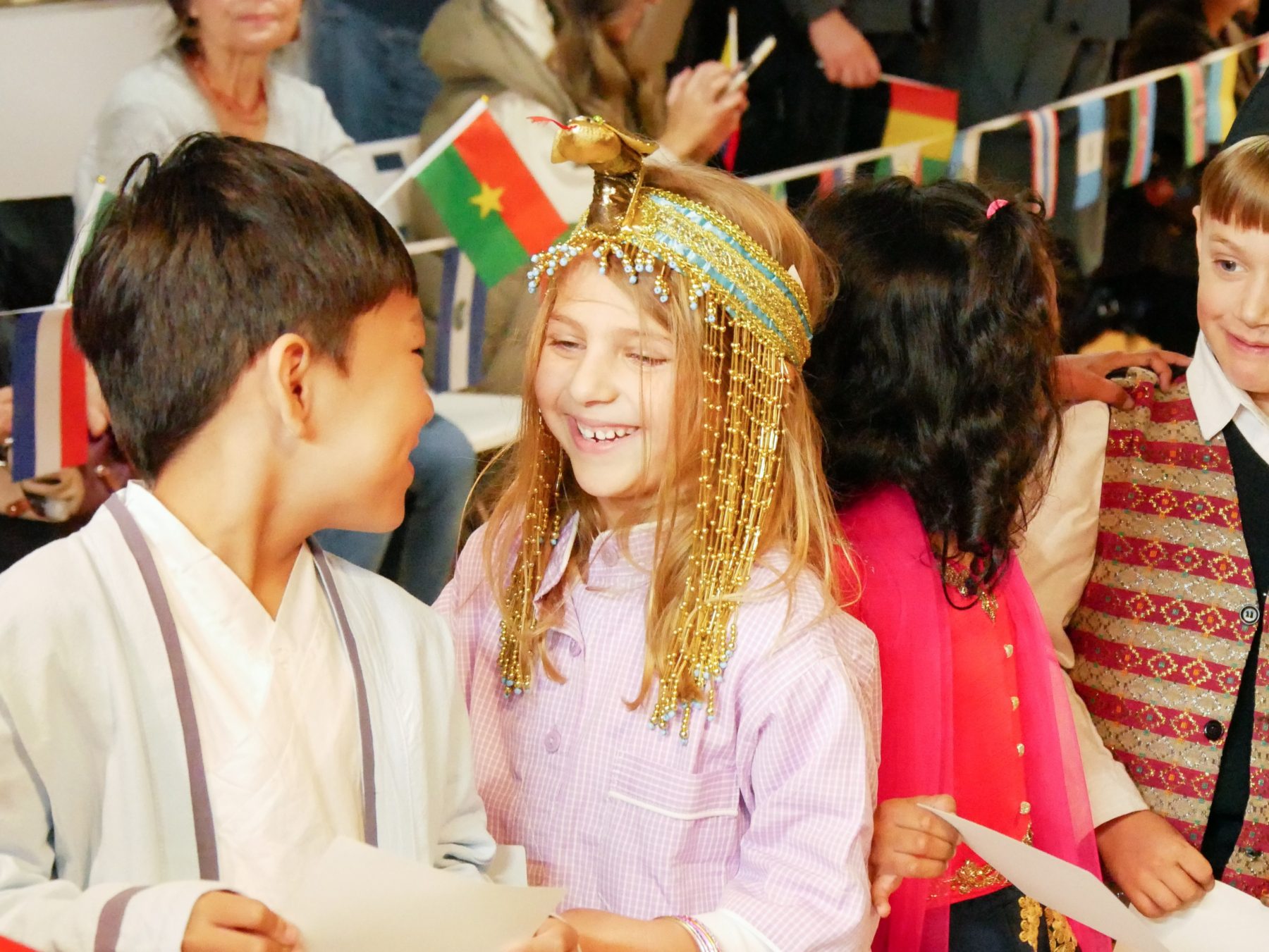 A line of students learning an international school curriculum dressed in cultural attire speaking to each other at a cultural event.