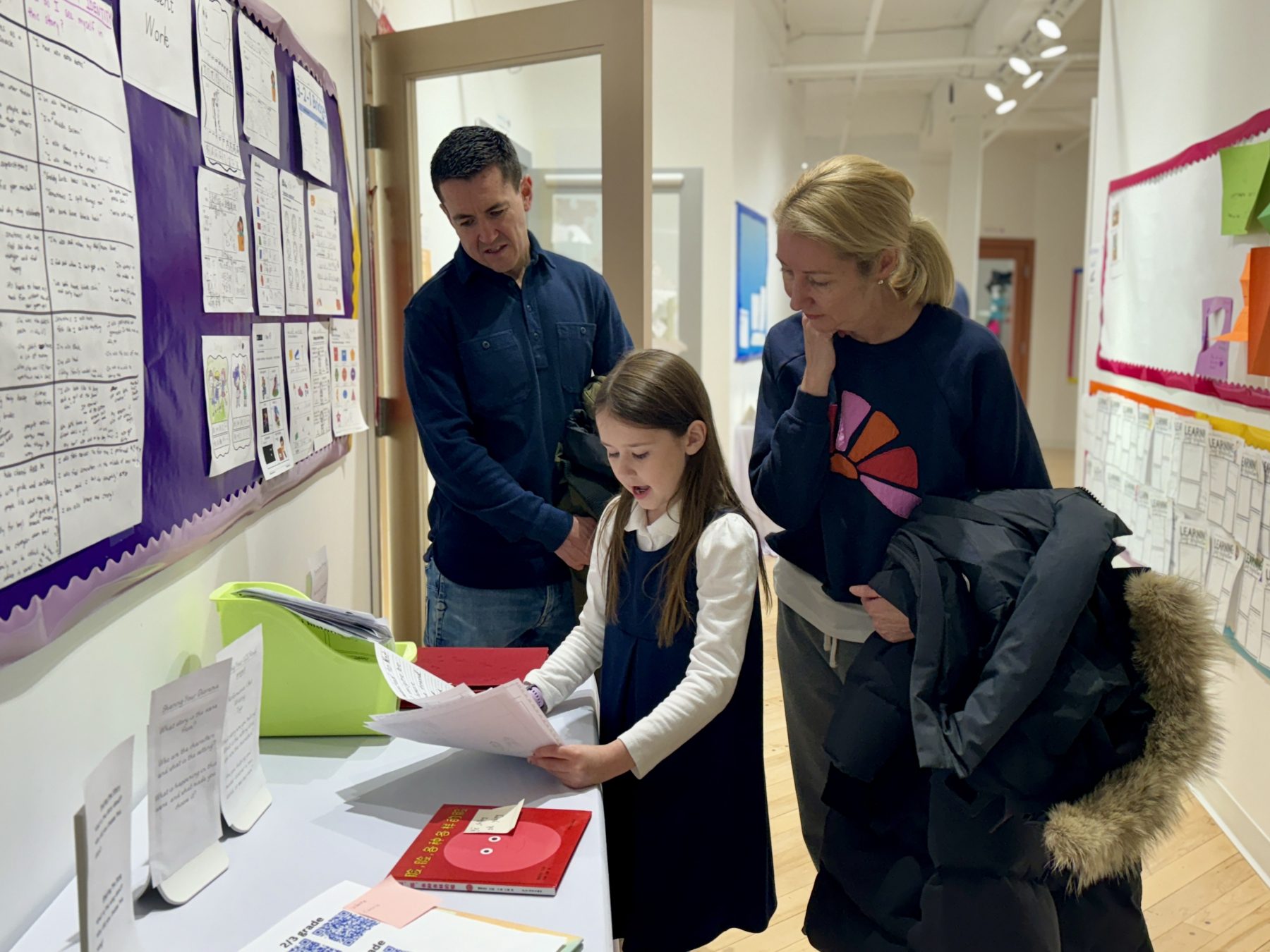 A girl shows her samples of work to her parents during her Student-Led conference. 