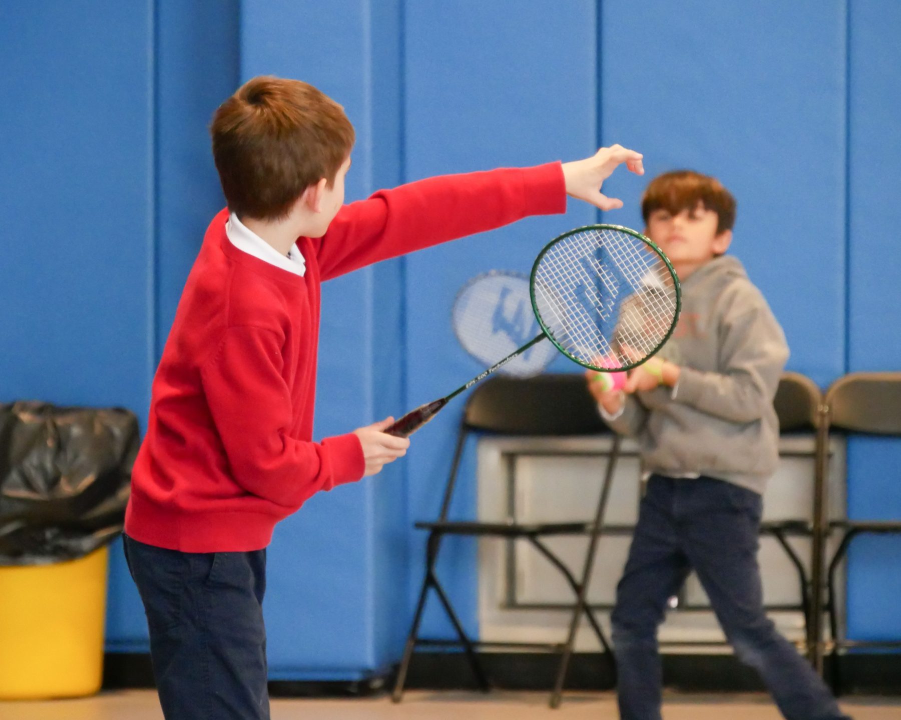 Students playing badminton in a gym.
