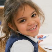 An international school student smiling while drawing during an art activity