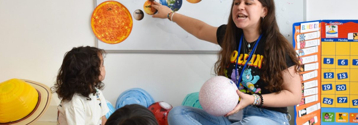 Teacher teaching Spanish to young learners. They are all sitting in circle on a rug.