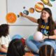 Teacher teaching Spanish to young learners. They are all sitting in circle on a rug.