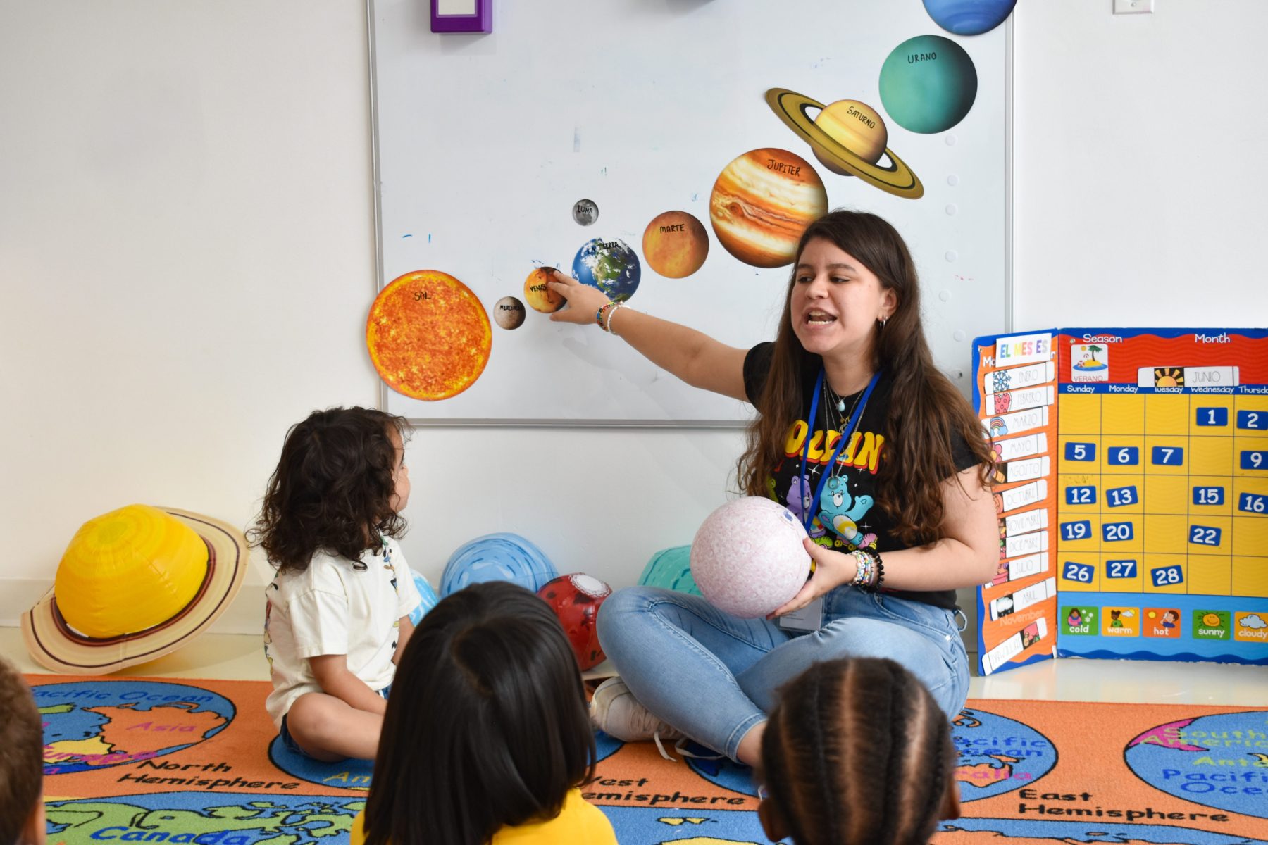 Teacher teaching Spanish to young learners. They are all sitting in circle on a rug.