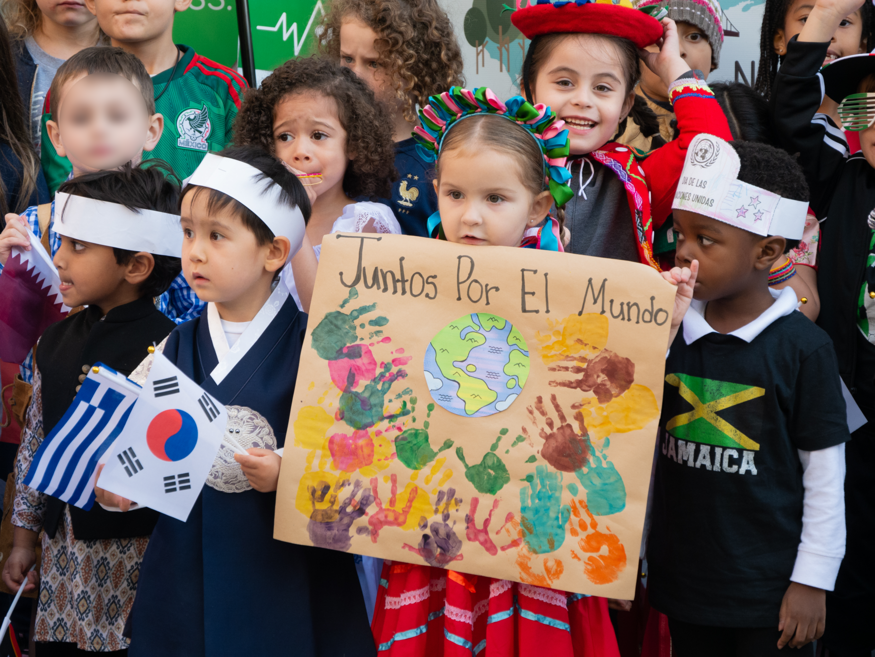 A class of primary students at Tessa International School holding up a poster of the earth written in Spanish.
