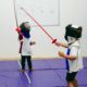 Students wearing protective clothing learn fencing in Tessa Afterschool class.