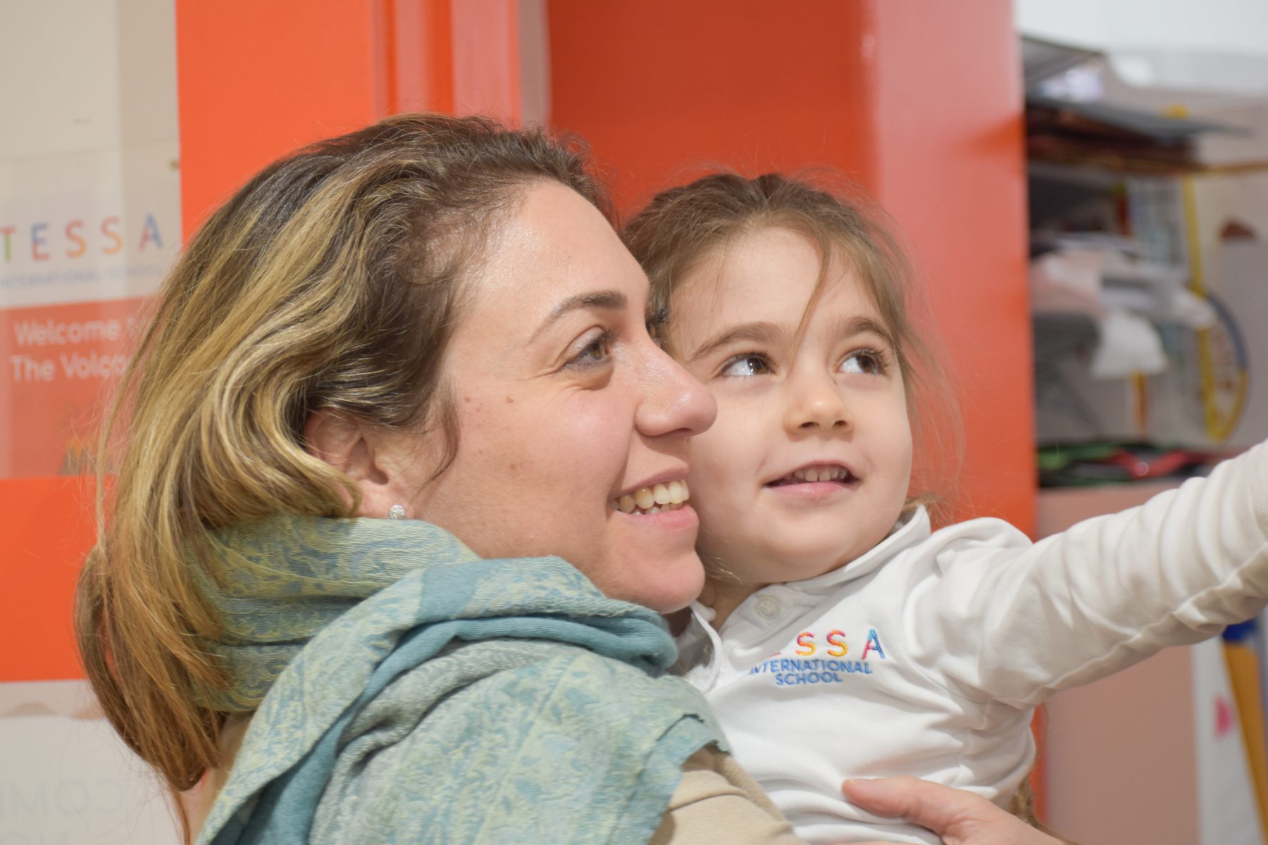 A mother proudly hugging her daughter and getting informed about her child's progress at Tessa International School