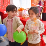 Two preschoolers delightfully hold balloons and sugar paintings to celebrate the Lunar New Year at Tessa International School in Hoboken, NJ.