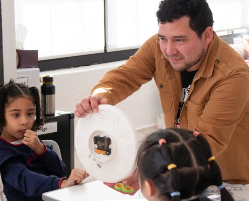 The STEM teacher shows the inner structure of a clock to Grade 1 students at Tessa International School.