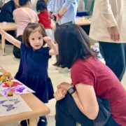 A toddler happily explaining to her mother the art activity during her IB PYP End-of-Unit Celebration