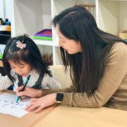 A kindergartener enhances her writing skills with her Mandarin teacher.