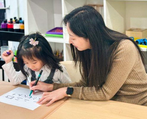 A kindergartener enhances her writing skills with her Mandarin teacher.