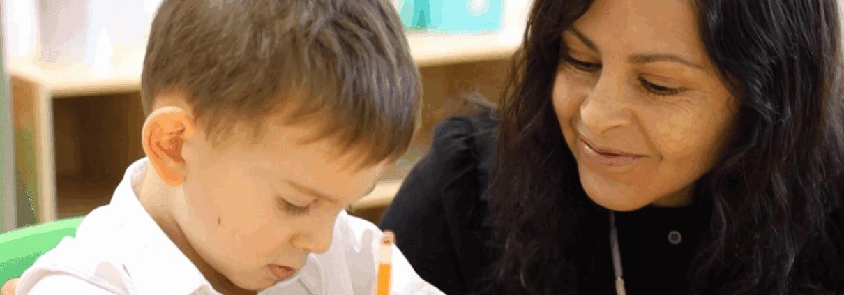 A Tessa preschooler works on his writing assignment under his teacher's guidance and care.
