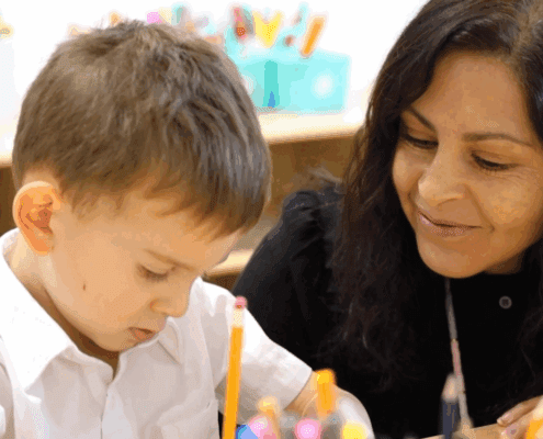 A Tessa preschooler works on his writing assignment under his teacher's guidance and care.