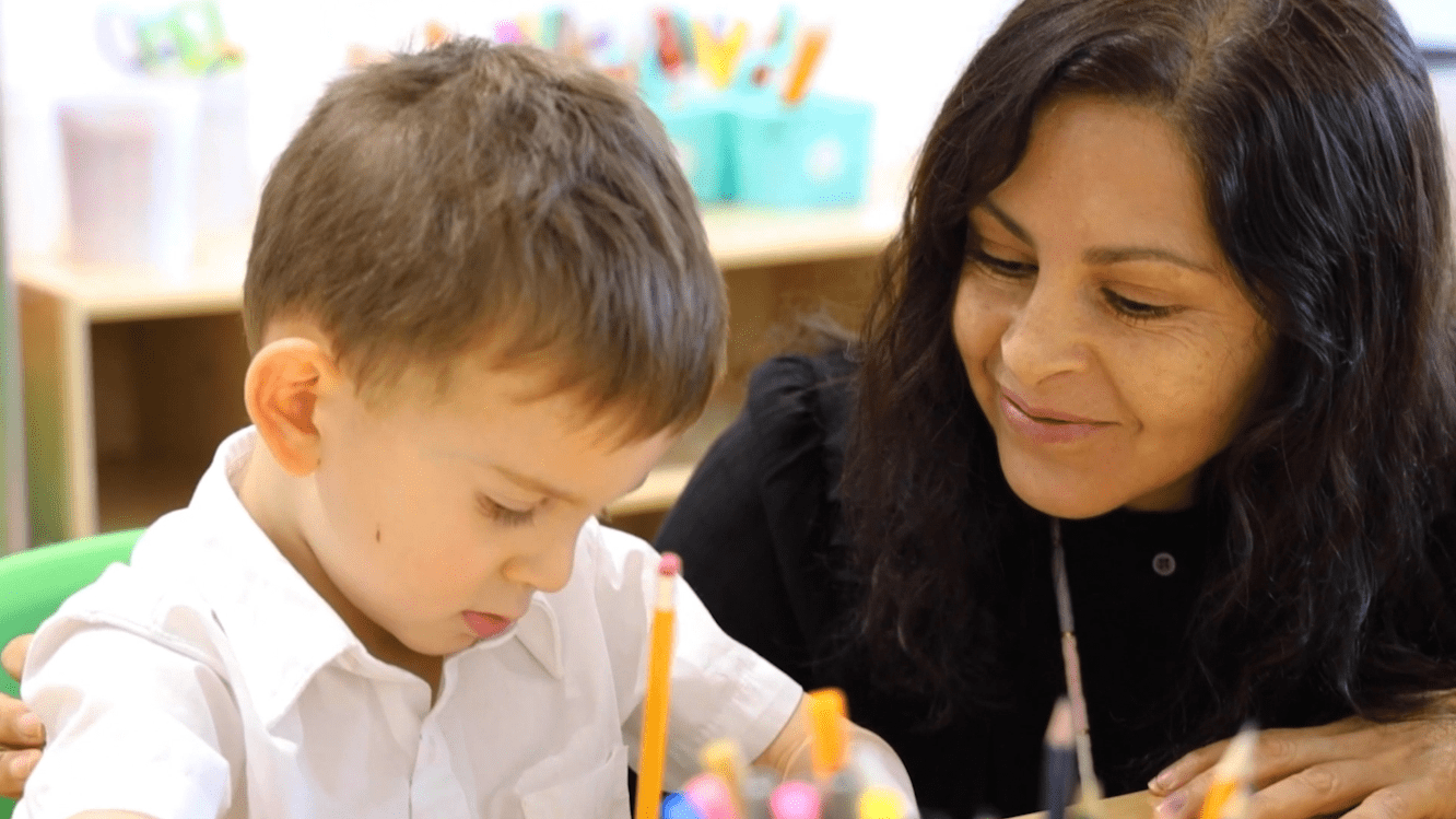 A Tessa preschooler works on his writing assignment under his teacher's guidance and care. 
